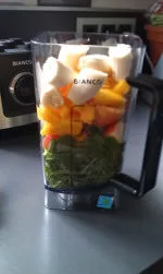 grünes Blattgemüse und Früchte im Mixbehälter